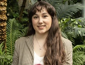 Portrait of author Margaret McDonald standing outdoors among greenery