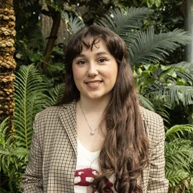 Portrait of author Margaret McDonald standing outdoors among greenery