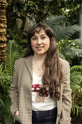Portrait of author Margaret McDonald standing outdoors among greenery