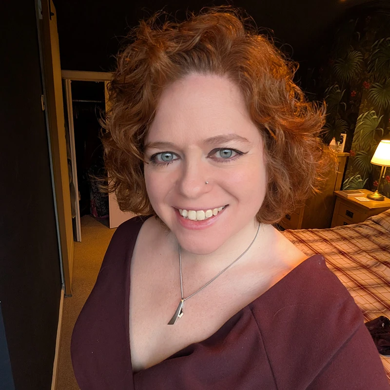 Portrait of Ceitidh Campbell smiling indoors, wearing a burgundy top and silver necklace.