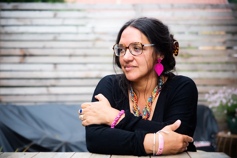 Poet Hannah Lavery seated outdoors wearing glasses and colourful jewellery.