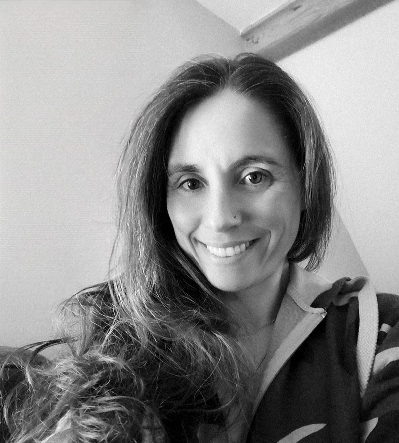 Keeks Mc smiling in a black and white portrait with long hair over one shoulder.