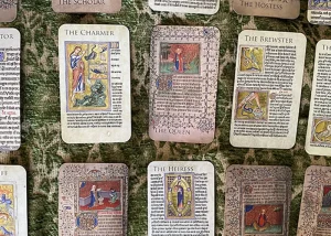 A selection of illustrated tarot cards from The Medieval Women Tarot deck laid out on patterned fabric, featuring medieval-style artwork and titles including The Heiress, The Widow and The Brewster.