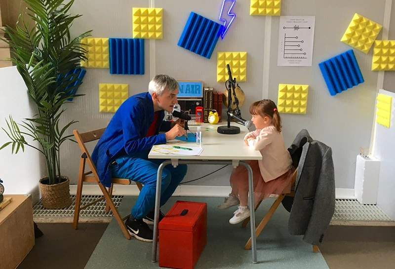 Performer interviewing a group of children at microphones during the interactive Experts Radio Lab event.