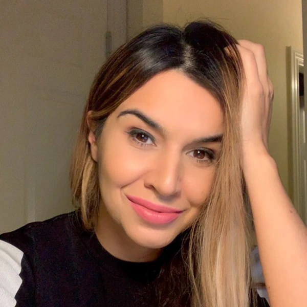 Fidan Meikle smiling at the camera with long highlighted hair and hand resting on her head.