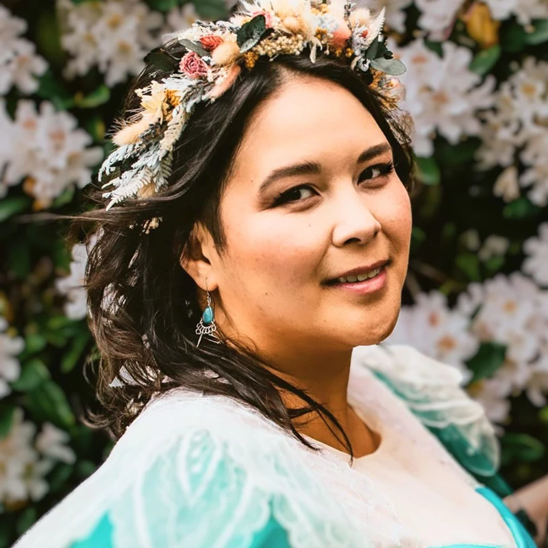 Katalina Watt smiling at the camera, with flowers in her hair and in the background.