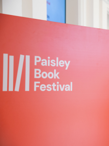 Orange sign with cream Paisley Book Festival logo
